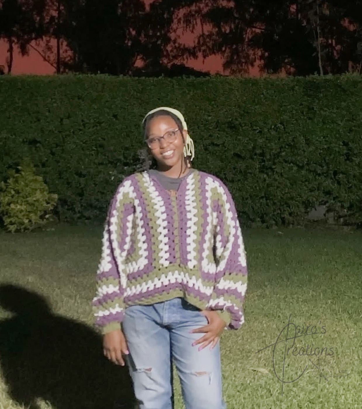 Green, purple and white crochet sweater worn outdoors at dusk